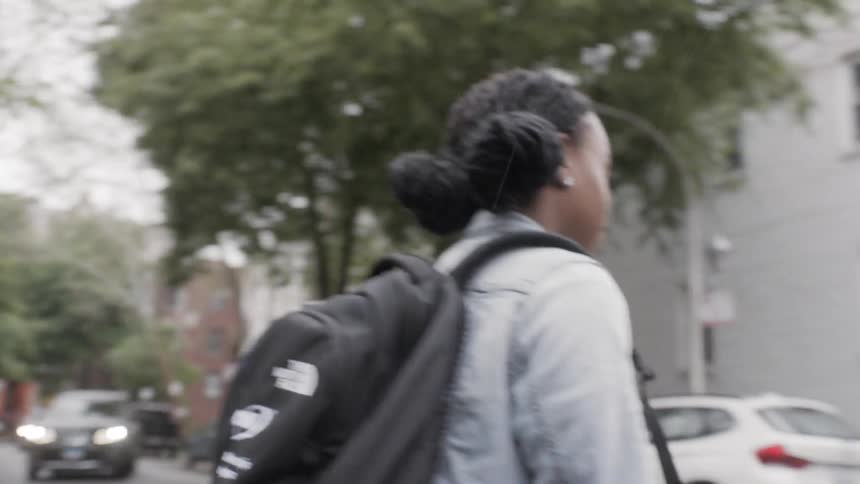 A woman walks outside with a backpack on