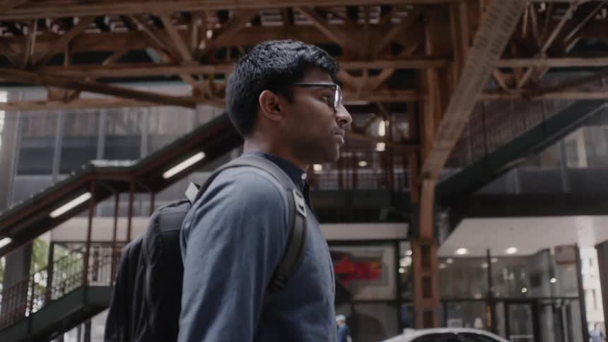 A pedestrian walks in a city with a backpack