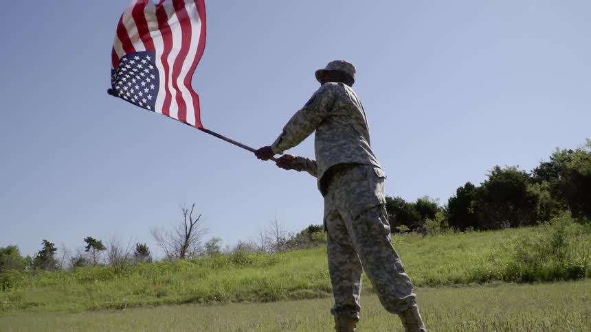 A soldier waves an american flag in the air