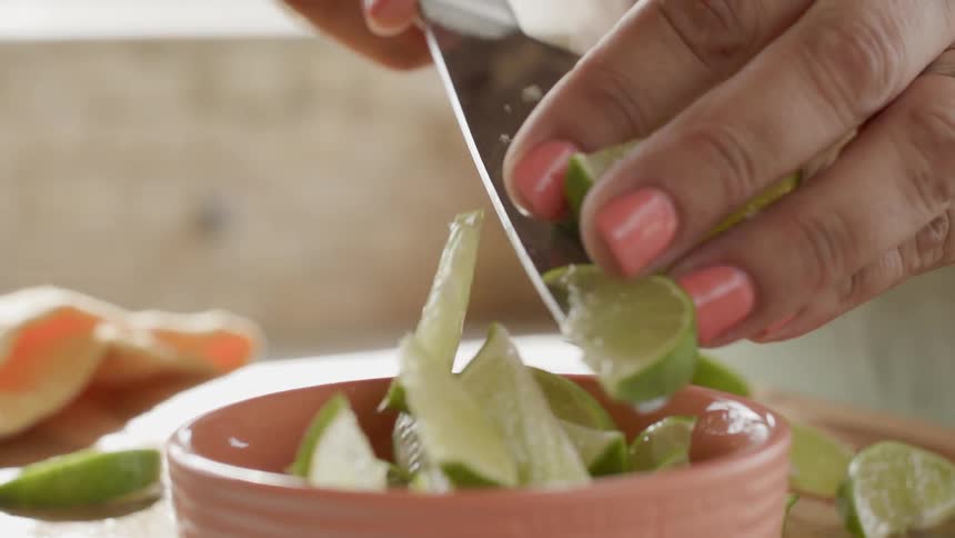 Pushing sliced limes off a knife into a bowl
