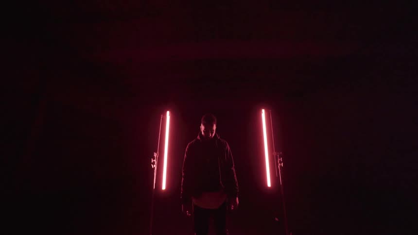 A man walks in a dark room with red lights