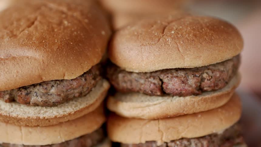 Hamburgers sit stacked on a tray