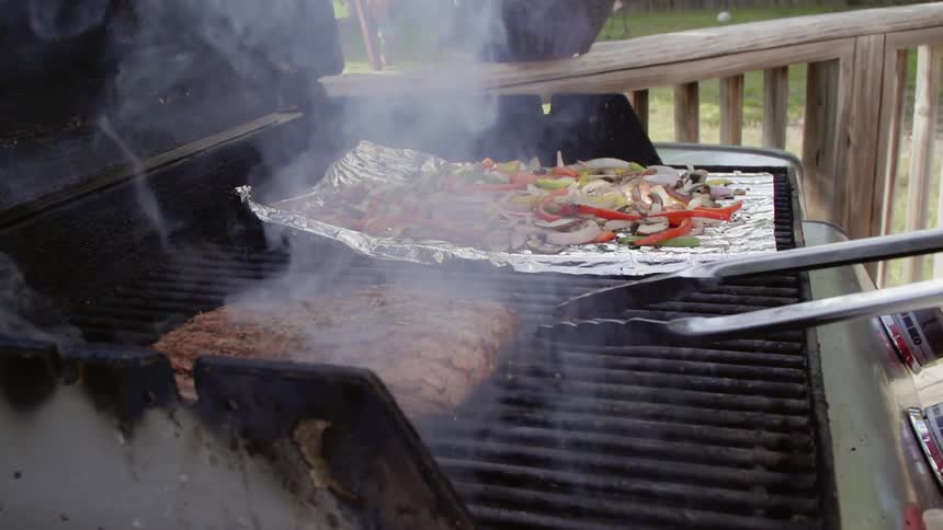 A steak and vegetables are cooked on a grill