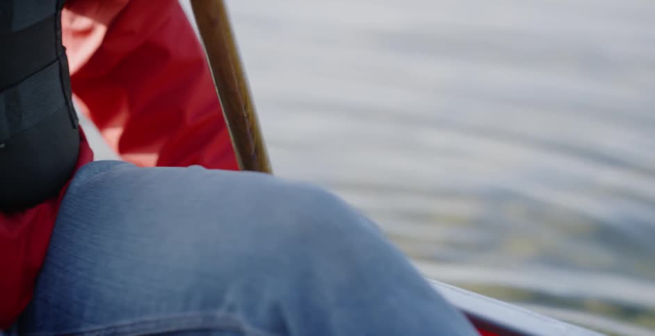 A person rows a boat with a wooden oar