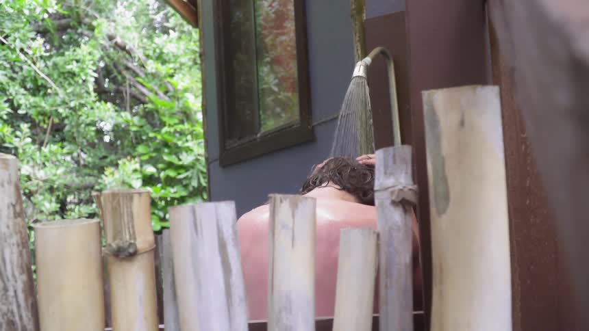 A man washes his hair in an outdoor shower