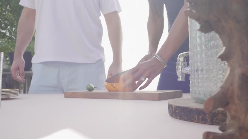 A woman slices a pepper on a cutting board outside