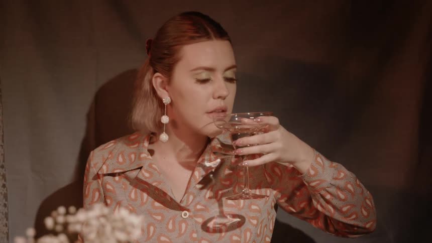 A woman is sipping from a champagne glass as she sits at a dinner table