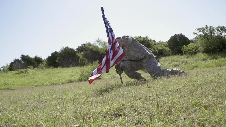 A soldier plants an american flag in the ground