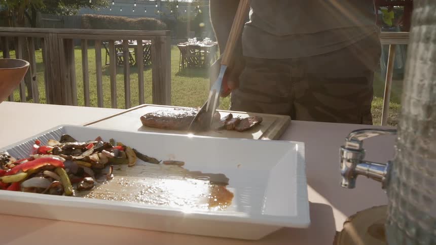 A steak being cut up on a table outside