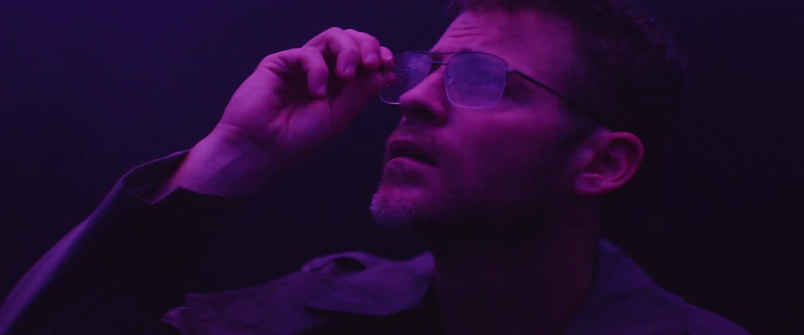 Man stands illuminated by colored lights at night