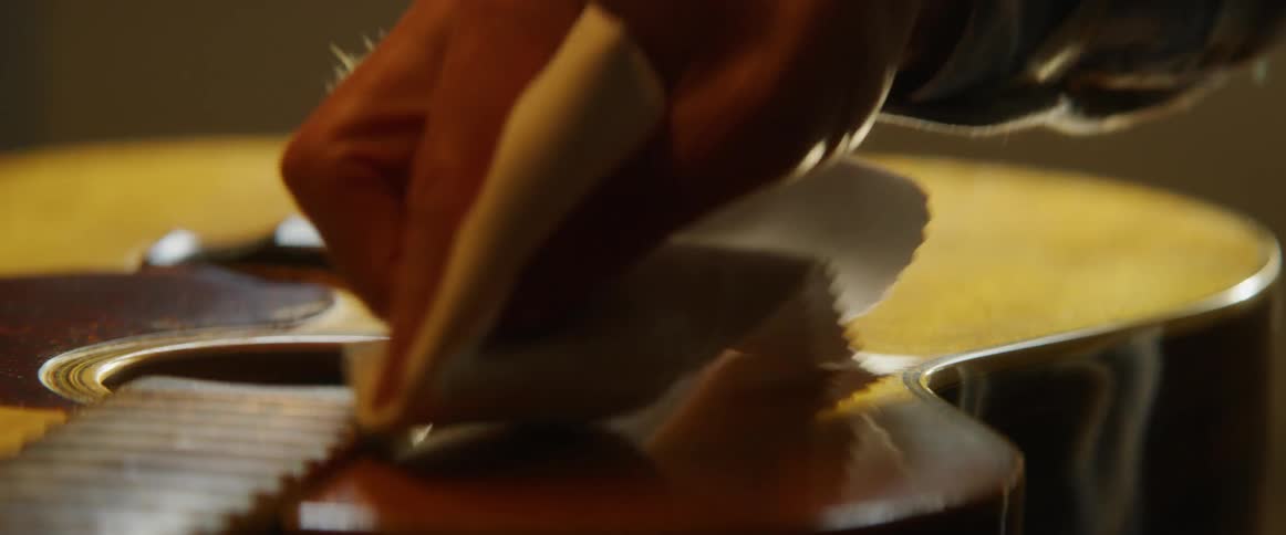 Man cleans a guitar with a cloth