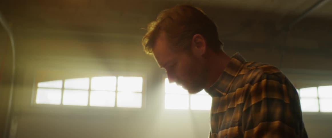 Man in a plaid shirt uses pliers in a garage
