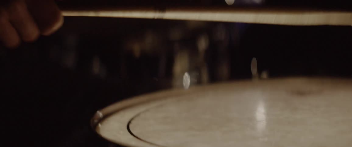 A drummer players in a dim room