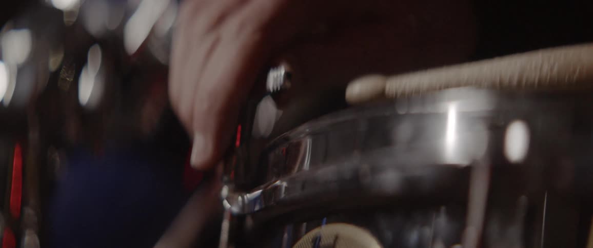 Person picks up a drum stick and hits a snare drum