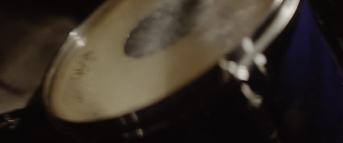A drummer is tapping on a snare drum inside in daylight