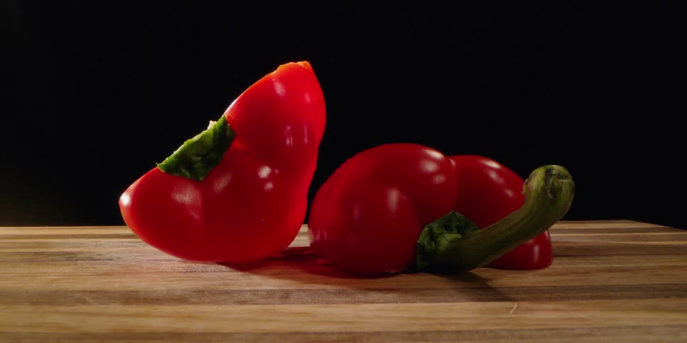 A halved red pepper sits on a wooden cutting board