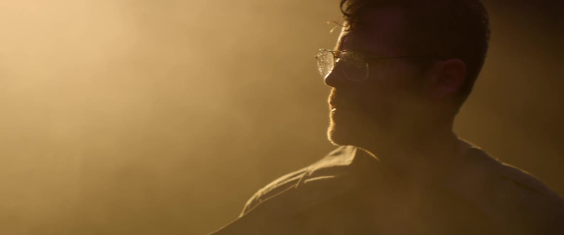 Dust floats around a man with dirty glasses