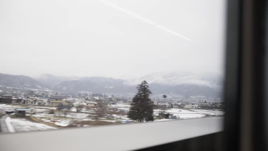 The train is moving past the snow covered fields