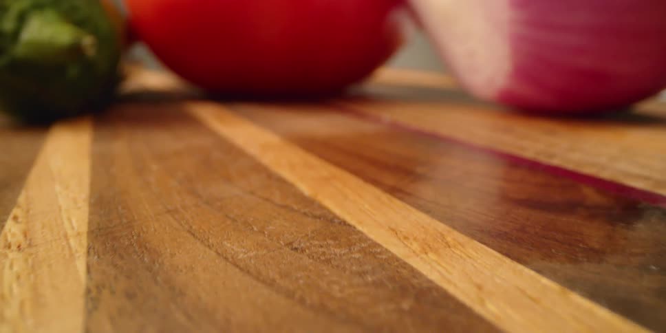 Assorted vegetables sit on a wooden cutting board