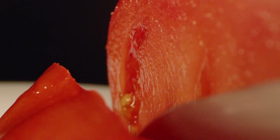 A knife slices through a tomato
