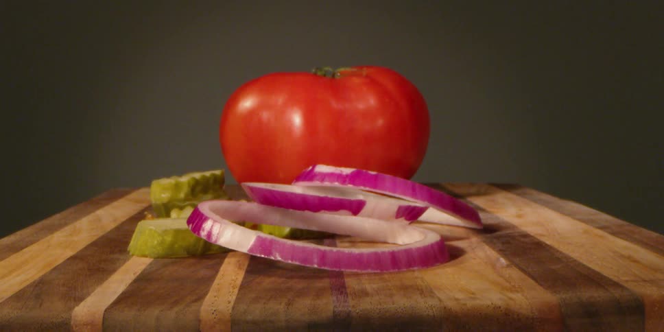 Pickles tomatoes and onions on a cutting board