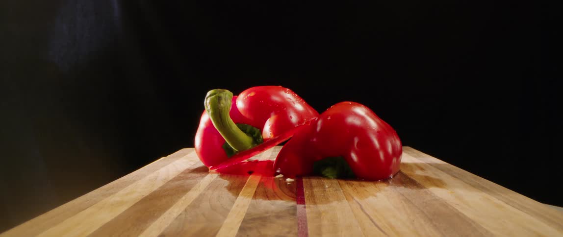 A red pepper sliced in half sits on a wooden cutting board