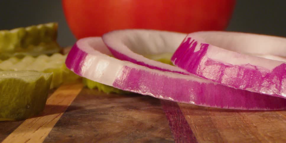 Sliced onions drop onto a wood board