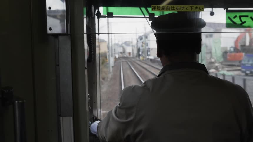 A driver navigates the train down a narrow track through a town