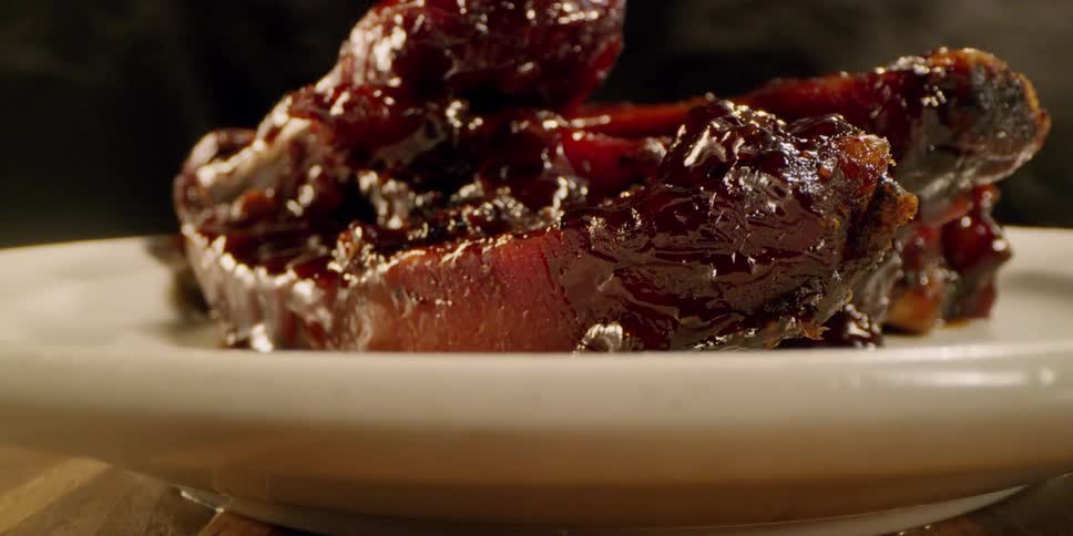 Pile of sauced meat on a plate with smoke around it
