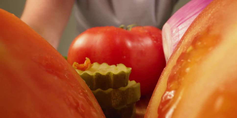 Tomato with moisture on it sits with other vegetables