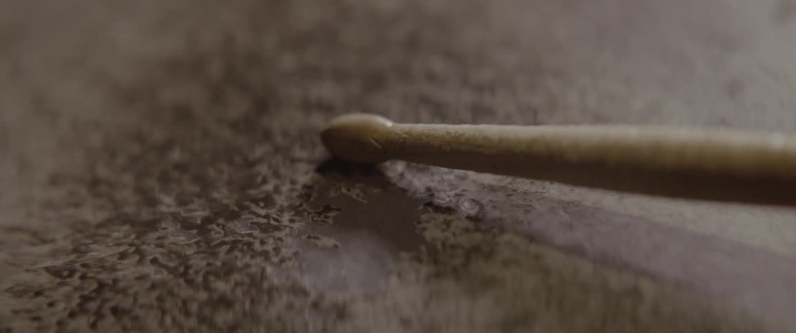 A drumstick rolls on a drumhead