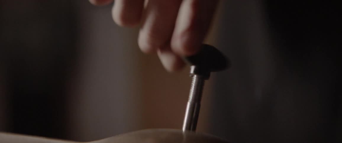 A person puts a bolt on a cymbal