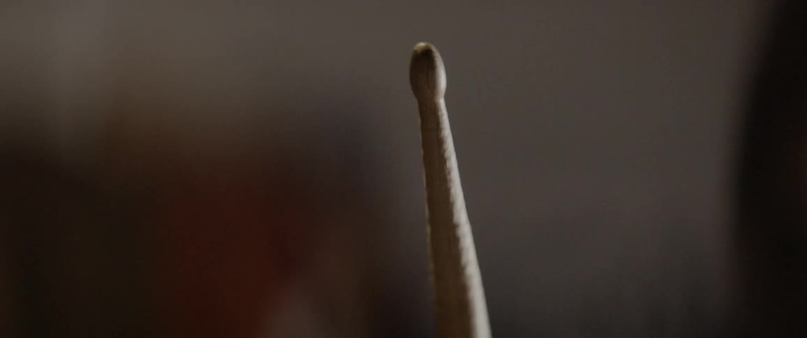A drumstick is being held steady in daylight