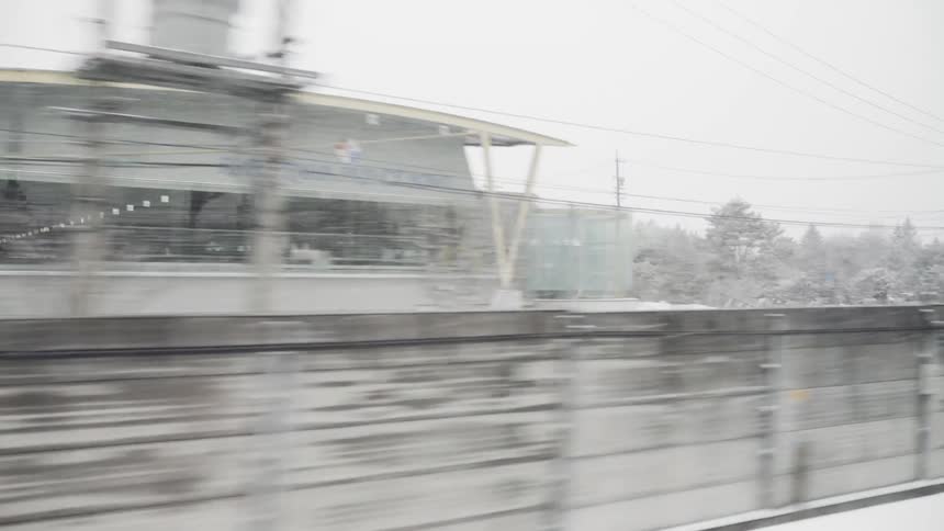 The train movest fast out of the station and into the snowy countryside