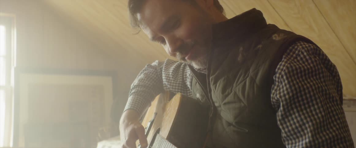A man plays guitar in a dusty attic