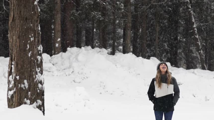 A woman stands outside in the falling snow