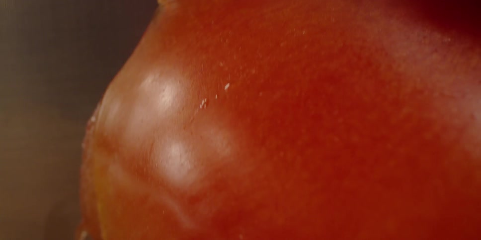 A knife is cutting through a tomato
