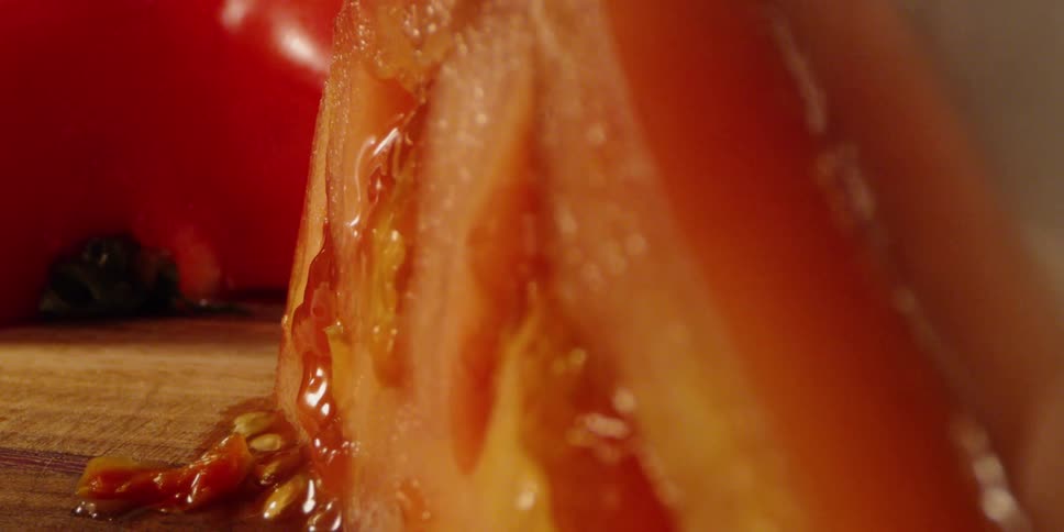 A person cuts a slice from a tomato