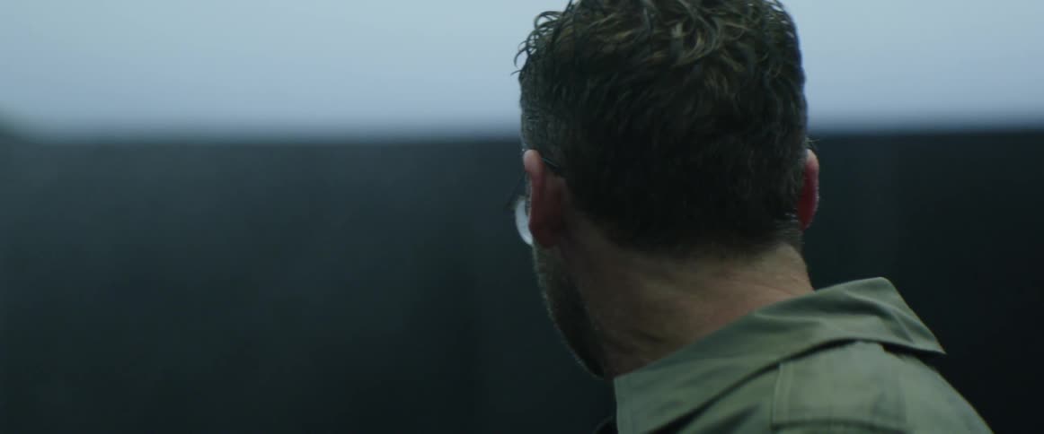 A man is turning his head to look around him outside in daylight