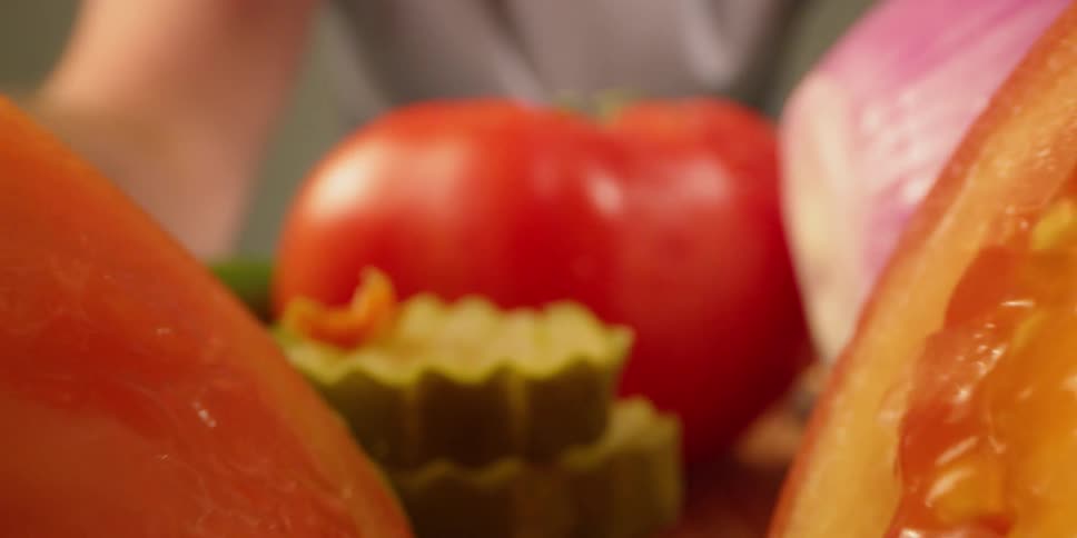 A large tomato is behind the other vegetables