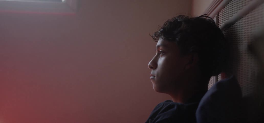 A boy is sitting in bed in the dark room