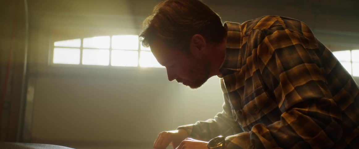 Man wearing a watch works at a table near a window