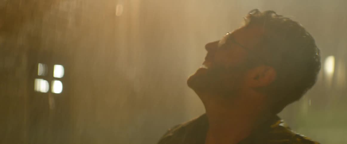 Man wearing glasses looks up at the falling rain