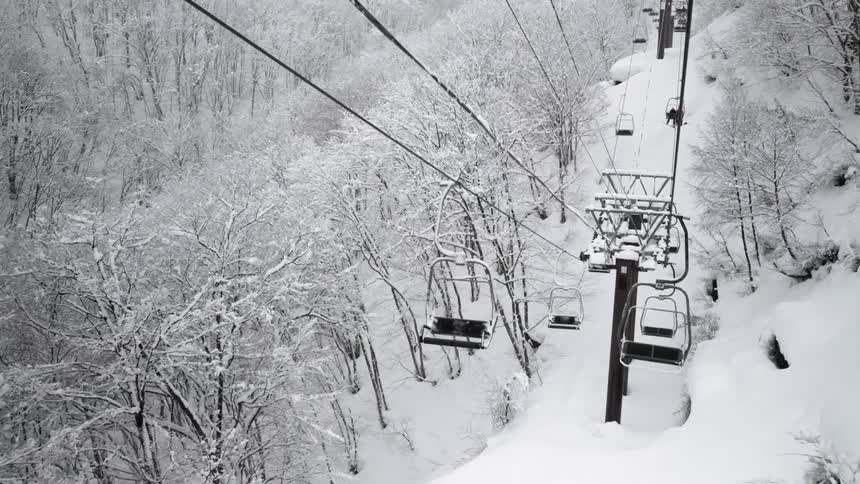 Empty ski lifts move up and down the snowy mountain