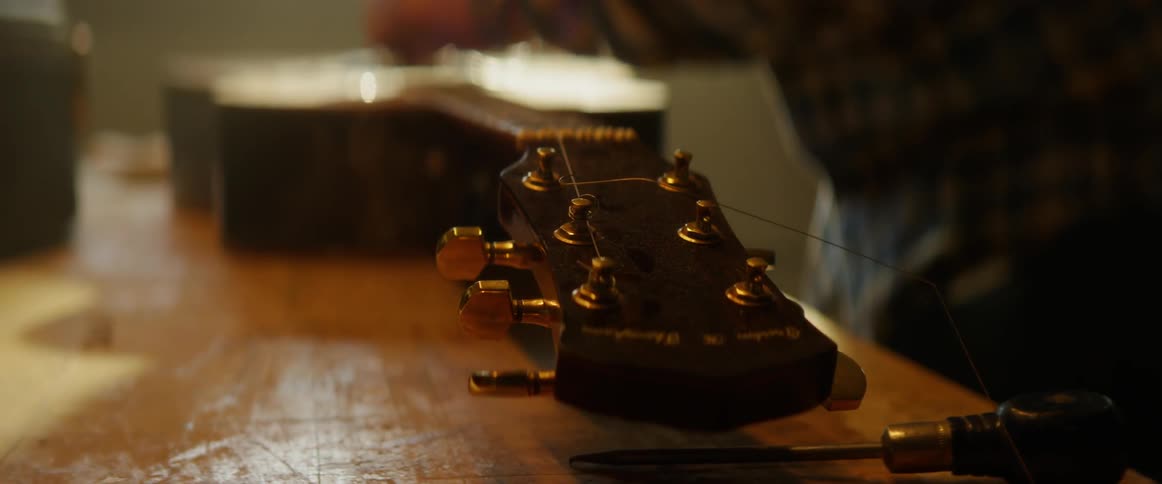 A man is tuning the guitar on the table