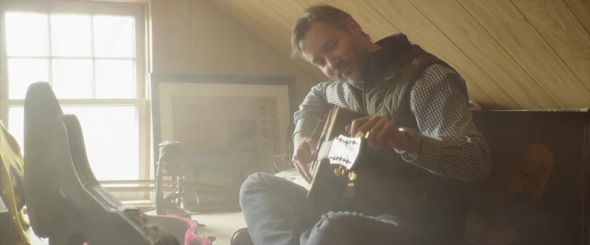 The man is playing the guitar in the attic