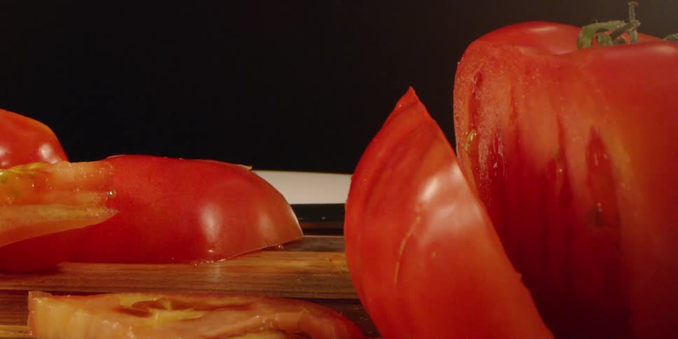 Sliced tomatoes are sitting on a cutting board