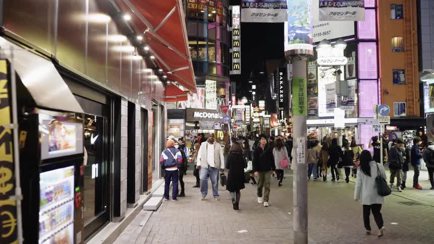 Pedestrians walk on a city street in Tokyo at night