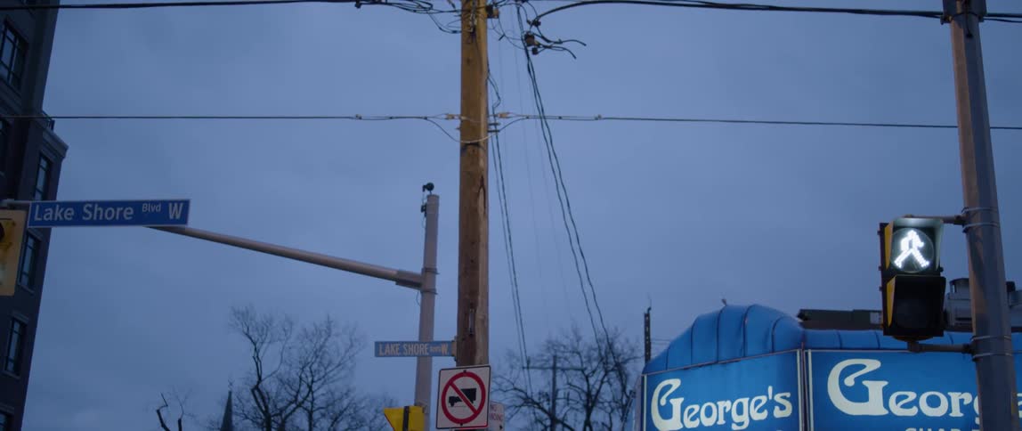 A telephone pole and street sign next to the awning of a business