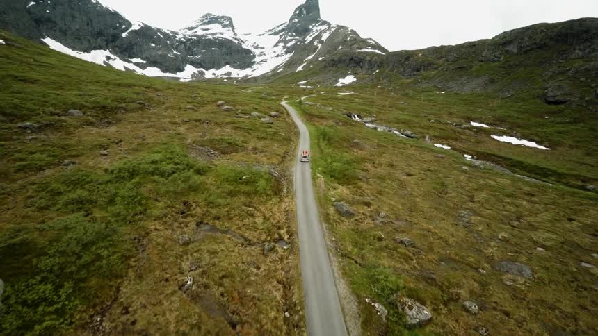 A vehicle drives on a road in the mountains